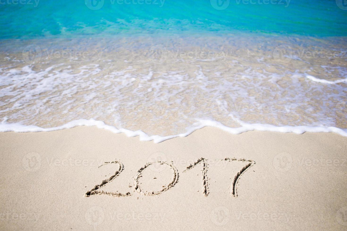 2017 handwritten on sandy beach with soft ocean wave on background photo