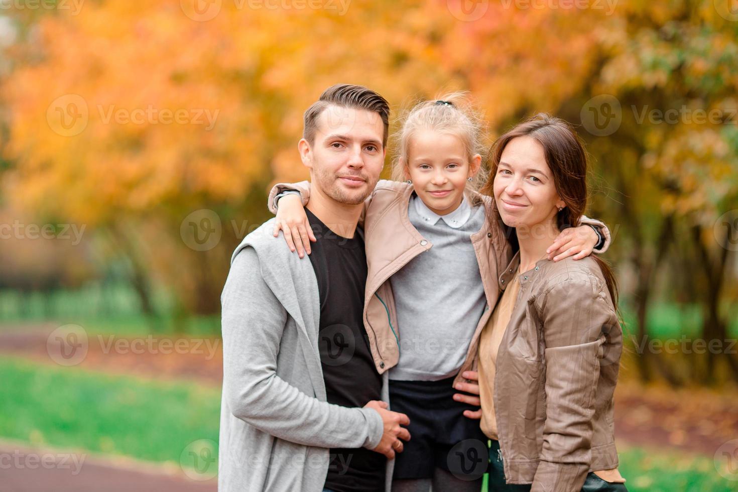 Portrait of happy family of three in autumn day photo