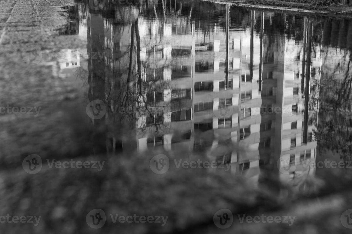 puddle in which an apartment building is reflected in black and white photo