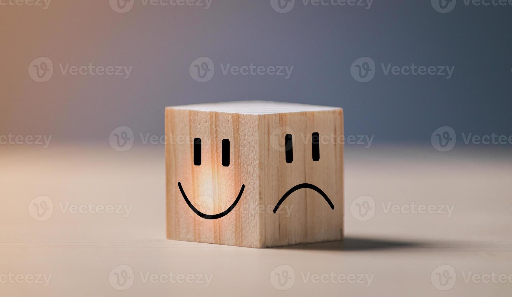 cara sonriente en el lado brillante y cara triste en el lado oscuro en un cubo de bloques de madera para una selección de mentalidad positiva. concepto de salud mental y estado emocional. foto