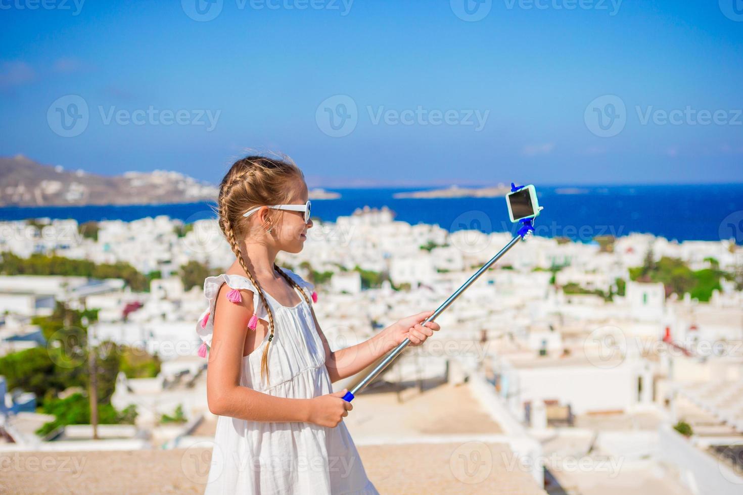 Little girl taking selfie background Mykonos town in Greece photo