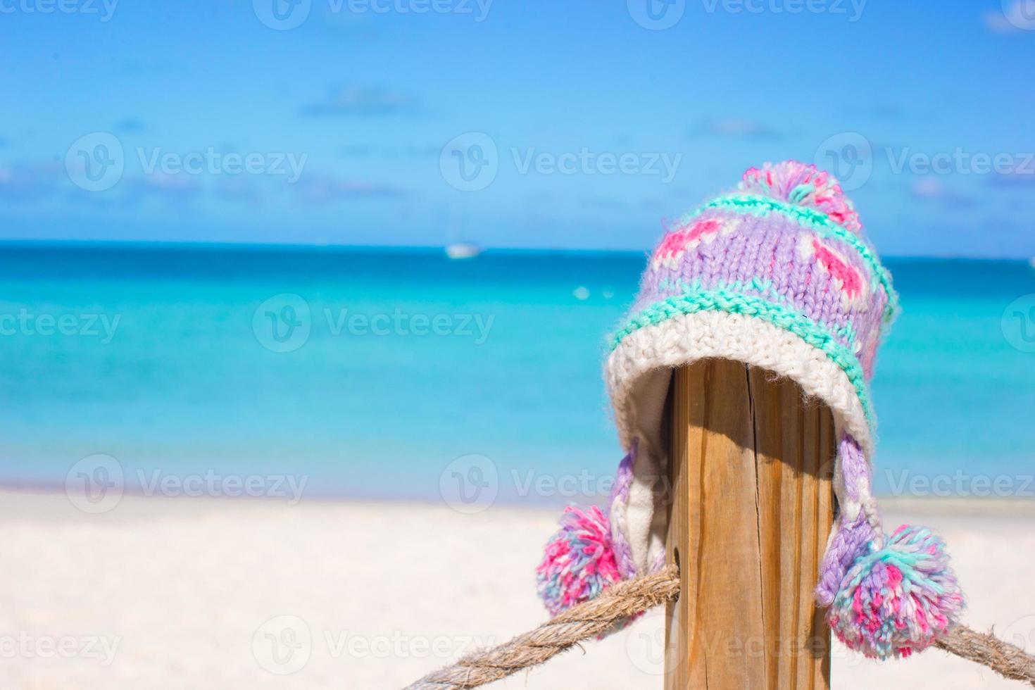 Closeup warm knitted cap on fence at tropical beach photo