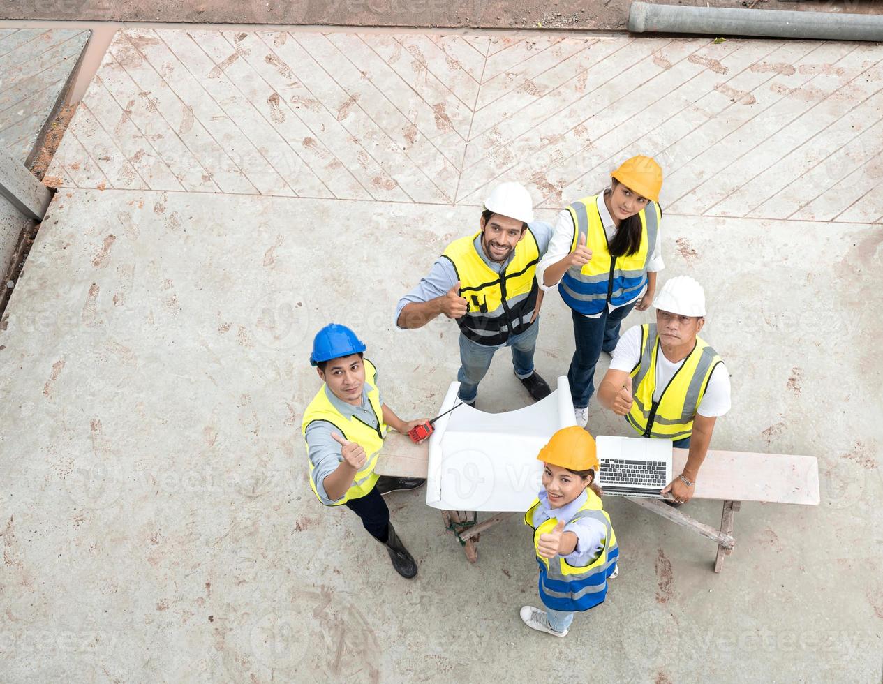 Engineer man and architect teamwork wear safety helmet meeting at construction site with blueprint for engineering project design, top view. High angle view of construction workers brainstorming. photo