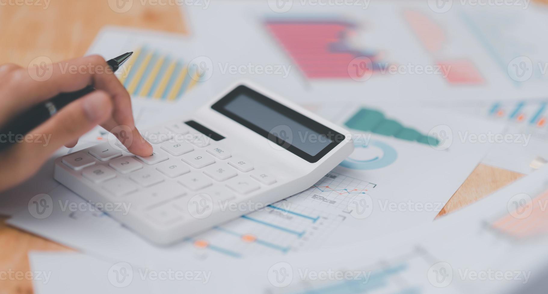 empresario calculando cifras en documentos financieros de la empresa con una calculadora, análisis de datos financieros de la empresa, planificación para evaluar y revisar presupuestos, concepto de finanzas e inversión foto