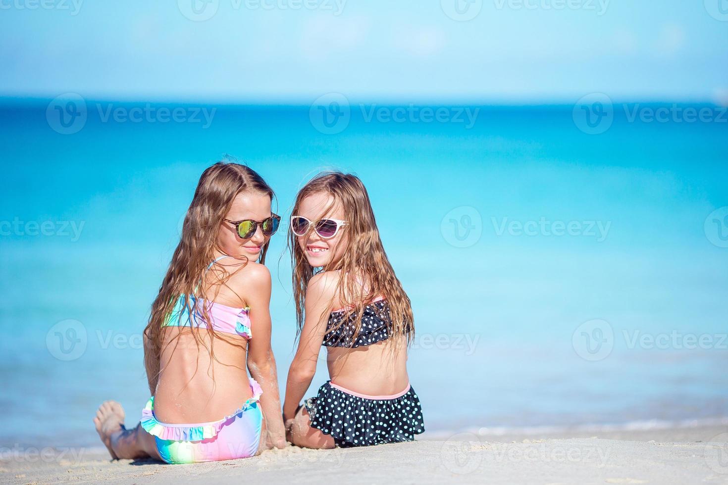 Two little happy girls have a lot of fun at tropical beach playing together photo