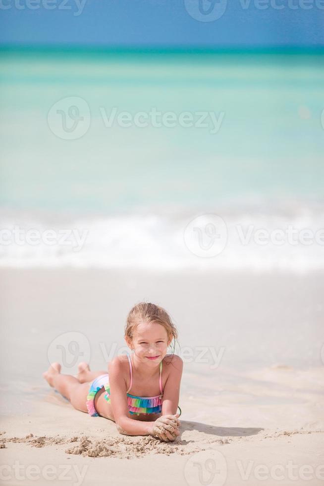 Adorable little girl at white beach during summer vacation photo