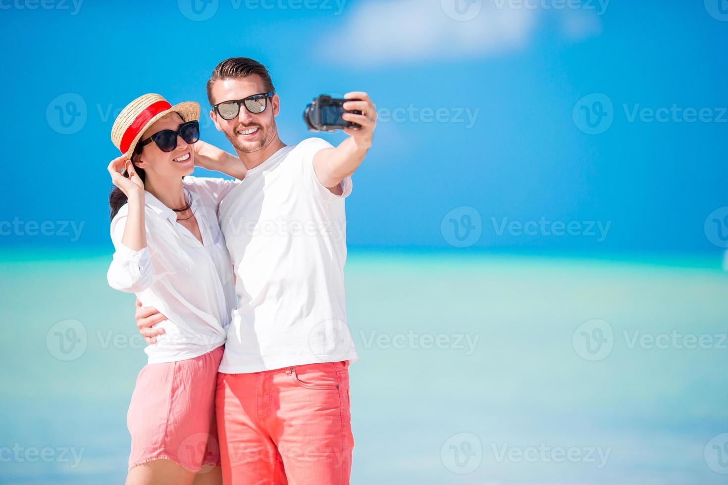 Couple taking selfie on the beach. Tourists people taking travel photos on summer holidays.