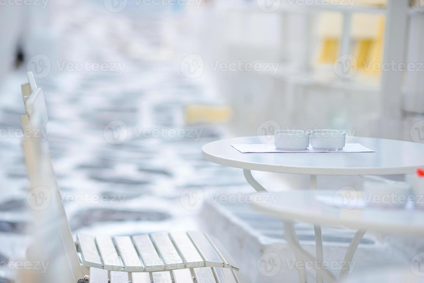 café al aire libre en una calle del típico pueblo tradicional griego en grecia. café en la mesa para el desayuno foto