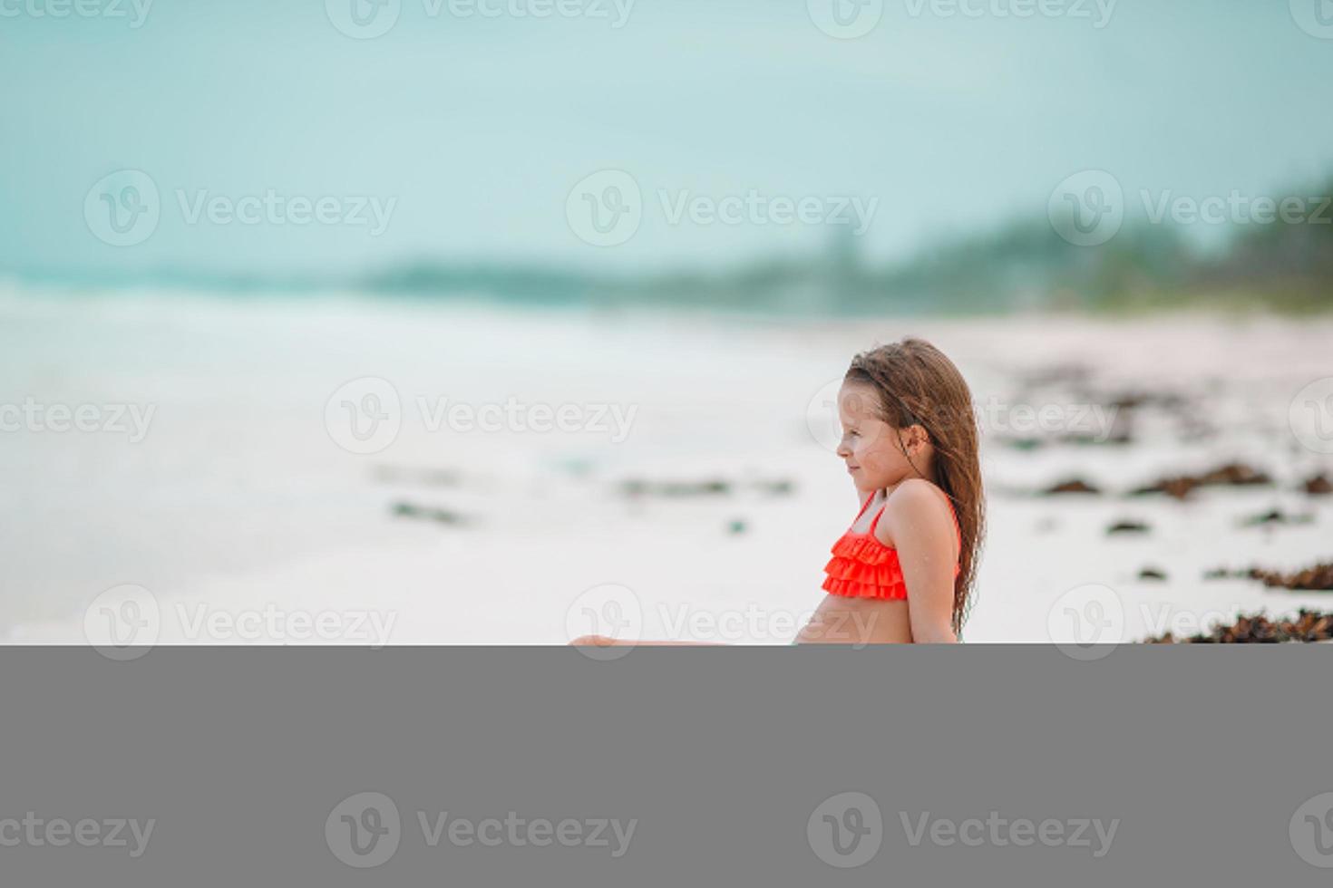 Adorable little girl have fun at shallow water on white beach photo