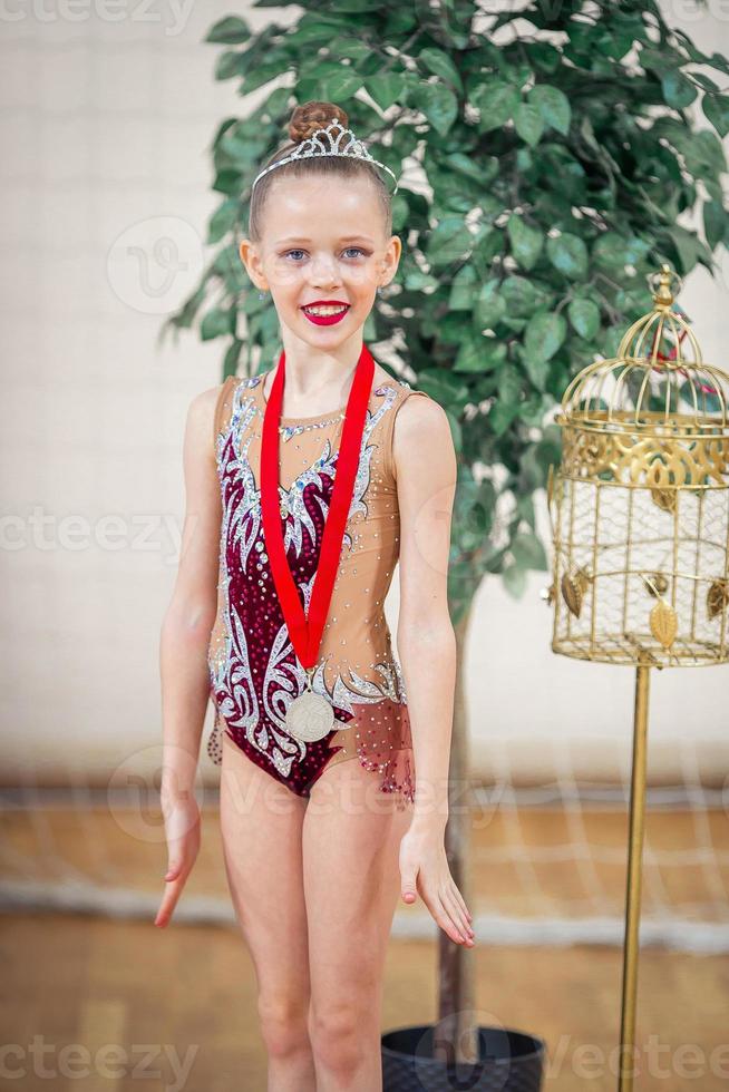 hermosa pequeña gimnasta entrenando en la alfombra y lista para las competiciones foto