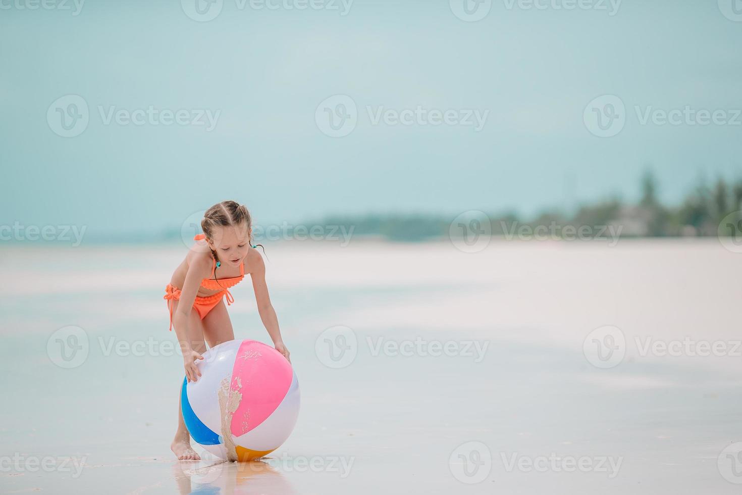 Little adorable girl playing on beach with ball photo