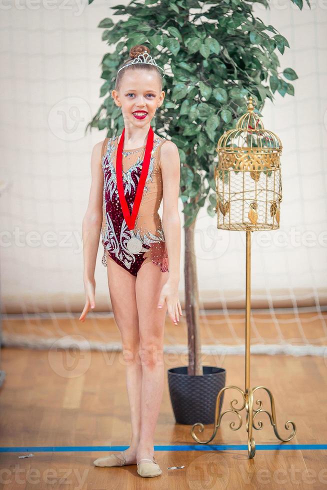 hermosa pequeña gimnasta entrenando en la alfombra y lista para las competiciones foto