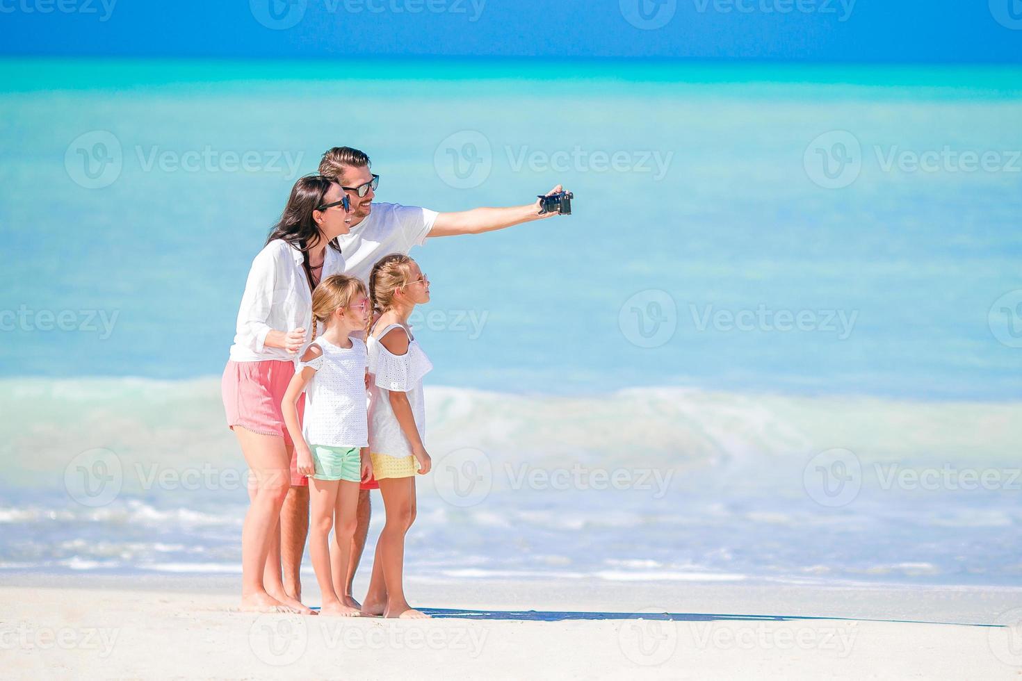 Family of four taking a selfie photo on the beach. Family vacation