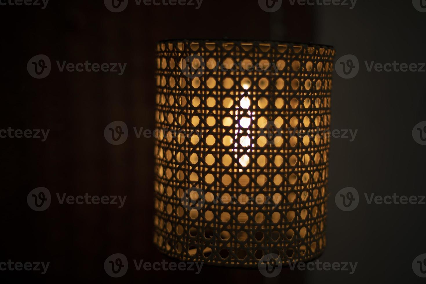 Lamp in dark. Wooden lampshade around incandescent lamp. photo