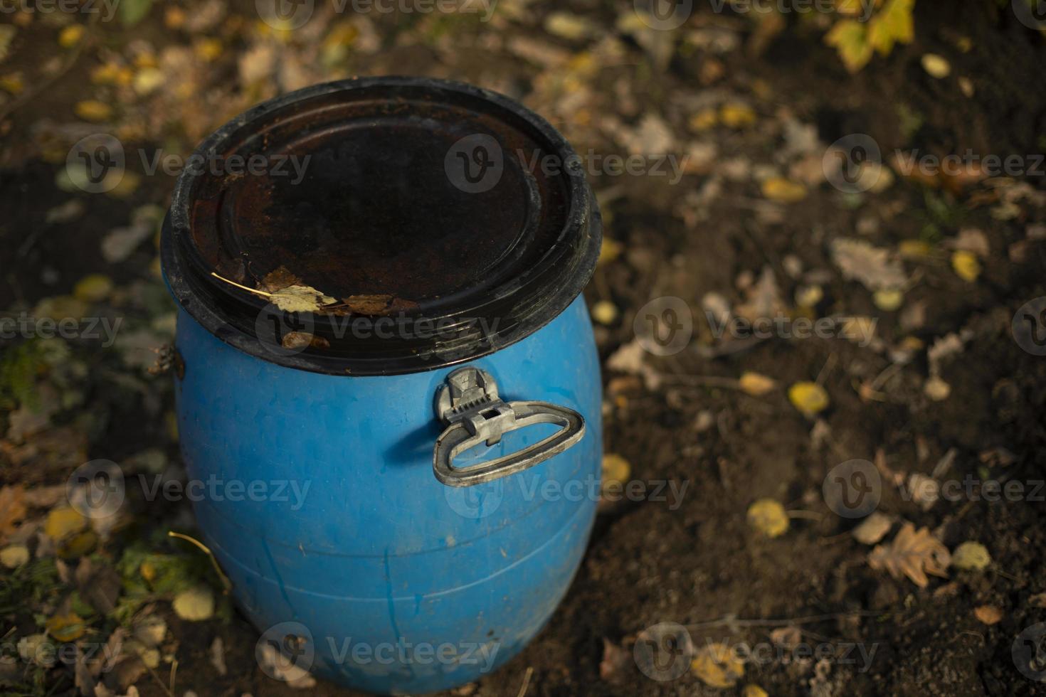 barril azul en el jardín. depósito de agua. barril de plástico para regar las plantas. foto