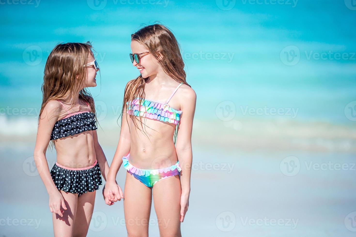 Little happy girls having a lot of fun together on the beach photo