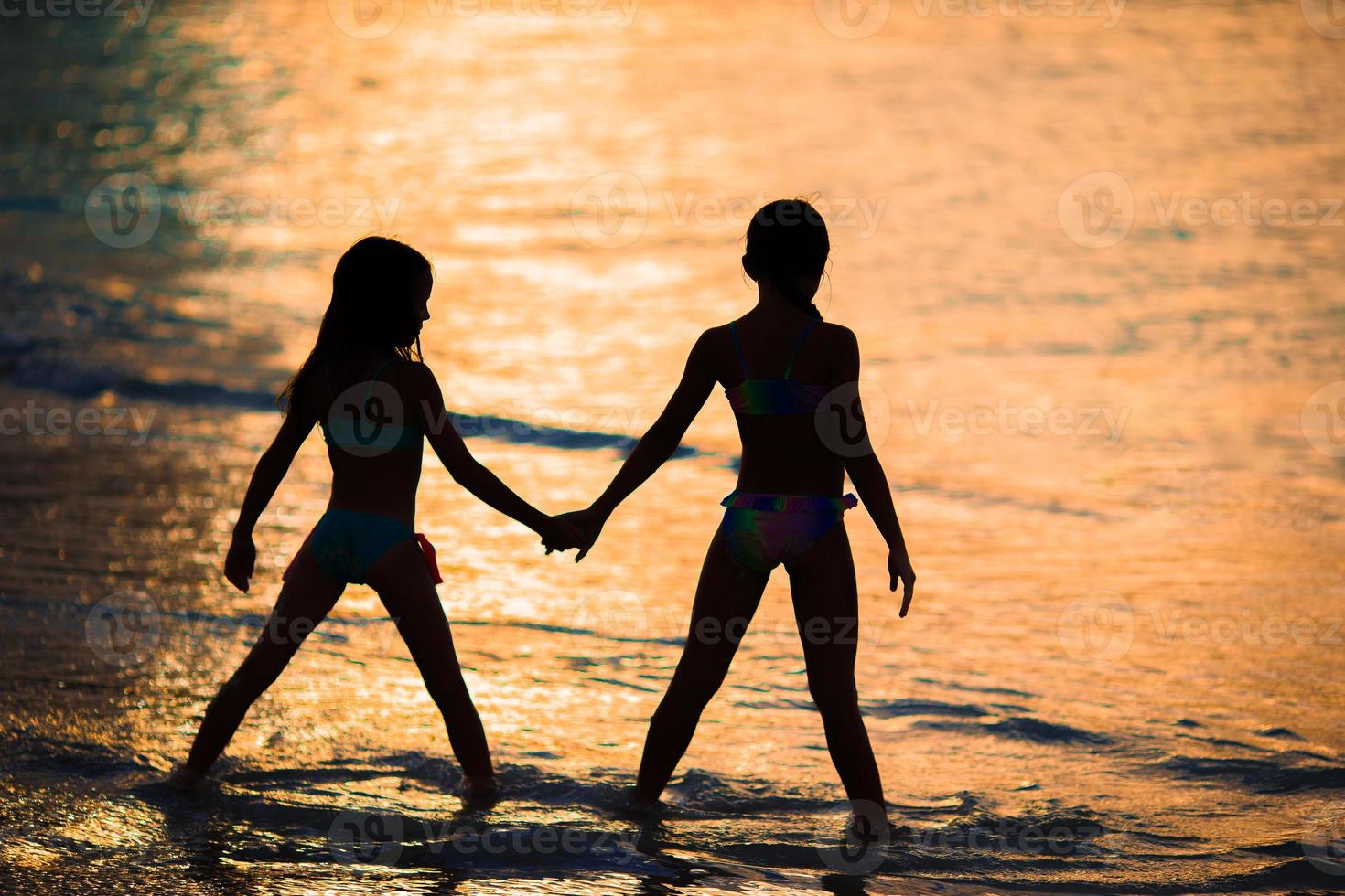 Adorable little girls on the beach with beautiful colorful sunset photo