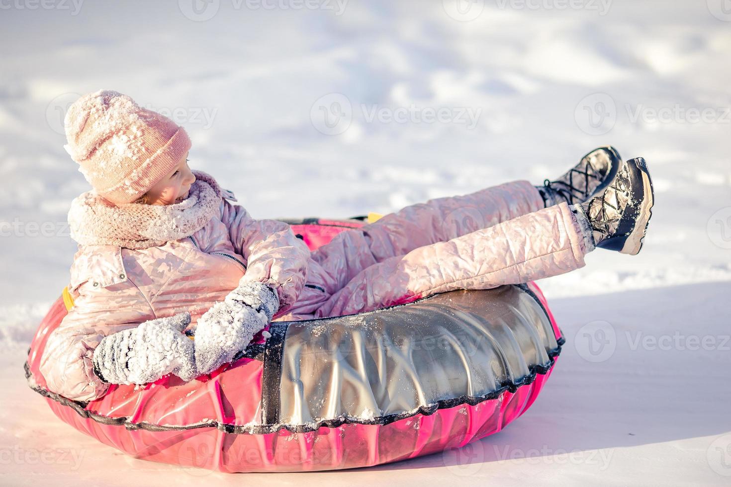 adorable niña feliz en trineo en invierno día de nieve. foto