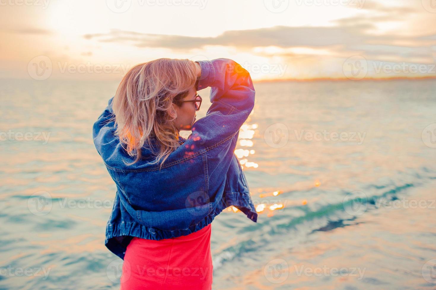 retrato de moda al aire libre de una chica elegante con chaqueta de jeans en la playa. foto