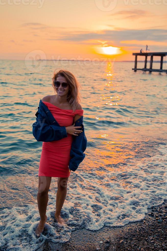 Outdoor fashion portrait of stylish girl wearing jeans jacket on the beach. photo