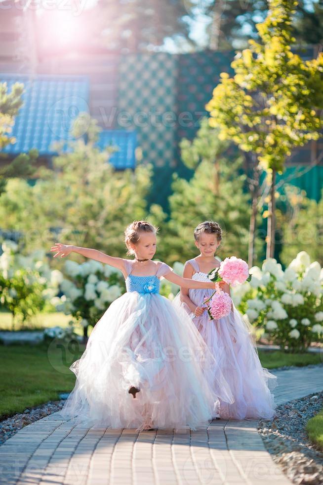 Two adorable girls with beautiful bouquets of roses in hands go to the wedding photo