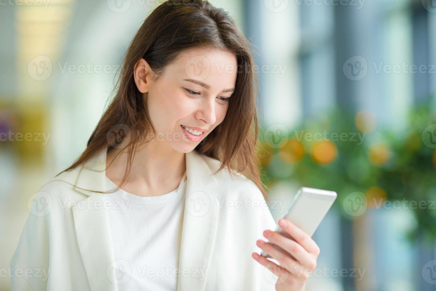 Young woman in international airport with her luggage and smartphone waiting for her flight photo