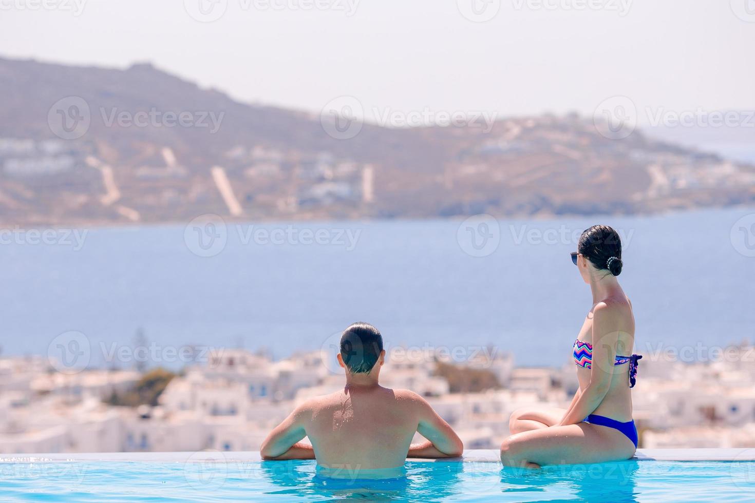 feliz joven pareja romántica relajándose al borde de la piscina foto
