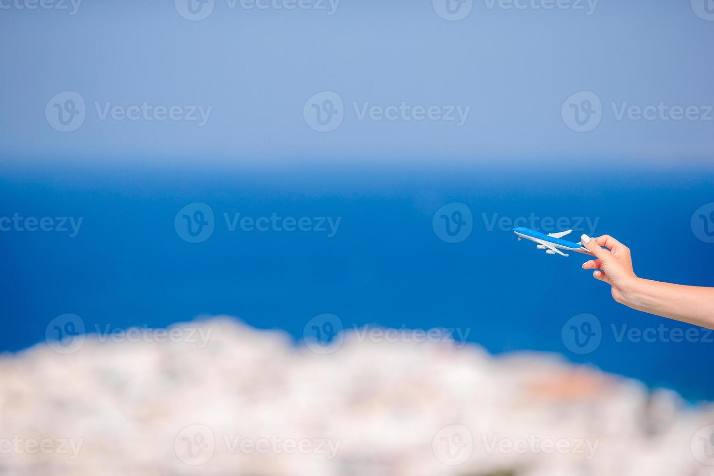 Tourist woman with toy airplane in hands background the old greek village photo