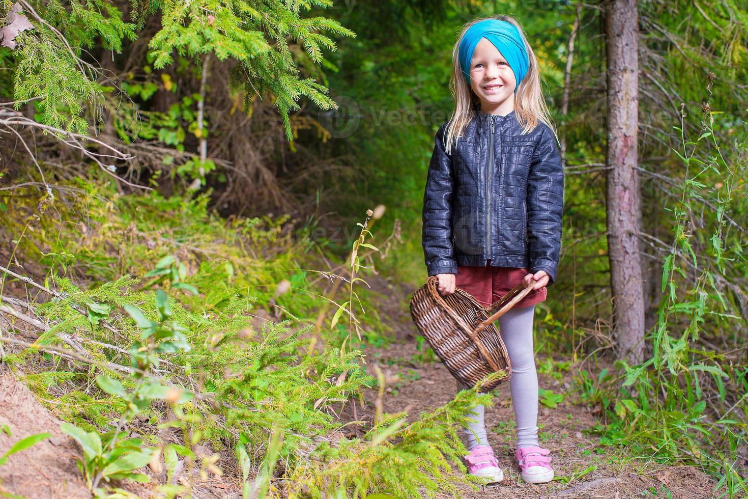 Little adorable girl pick up mushrooms in autumn forest photo