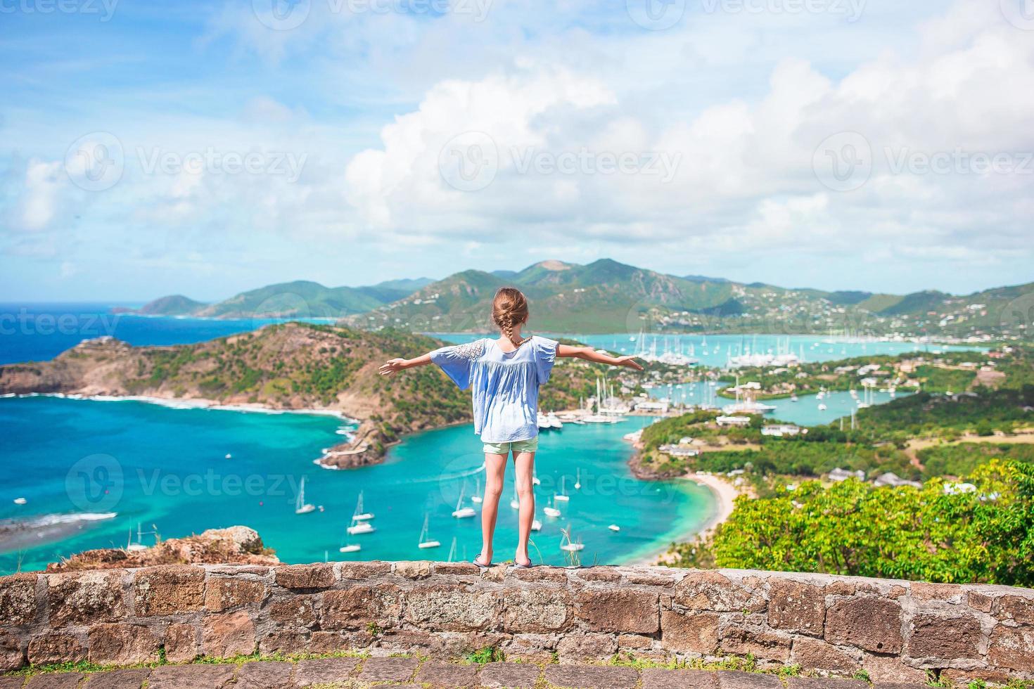 Little adorable kid with beautiful famous view. View of English Harbor from Shirley Heights, Antigua, paradise bay at tropical island in the Caribbean Sea photo