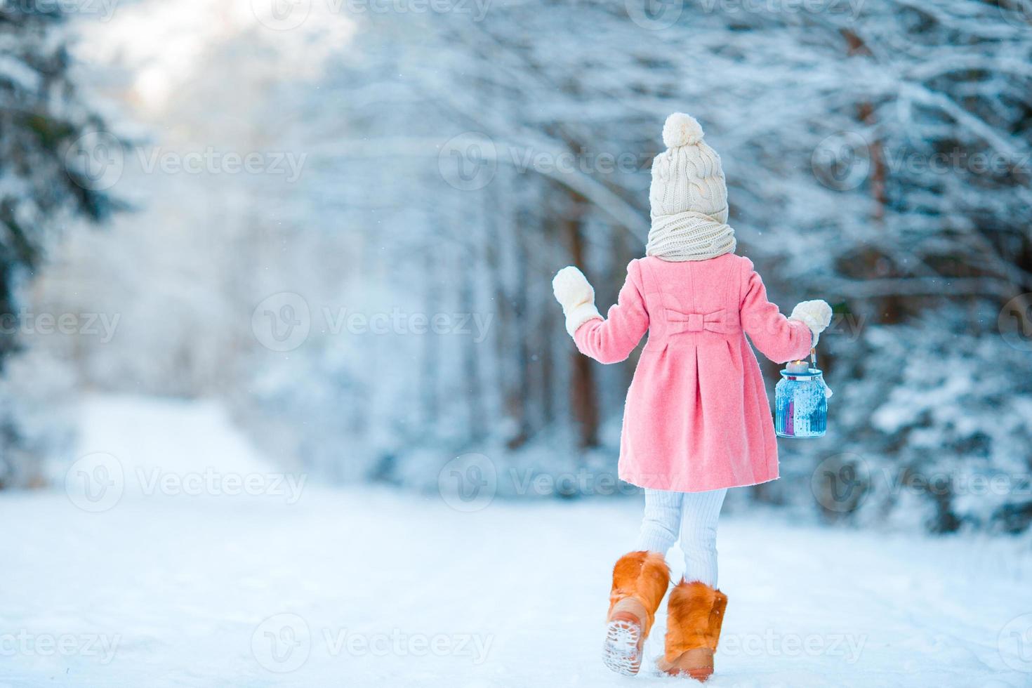 Little girl with latern in frozen forest on Christmas eve photo