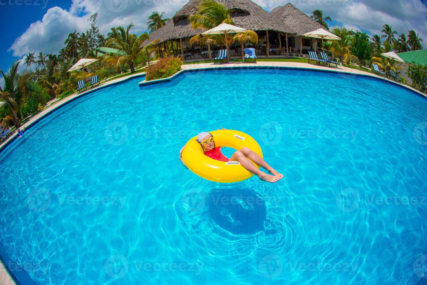 Little happy adorable girl in outdoor swimming pool photo
