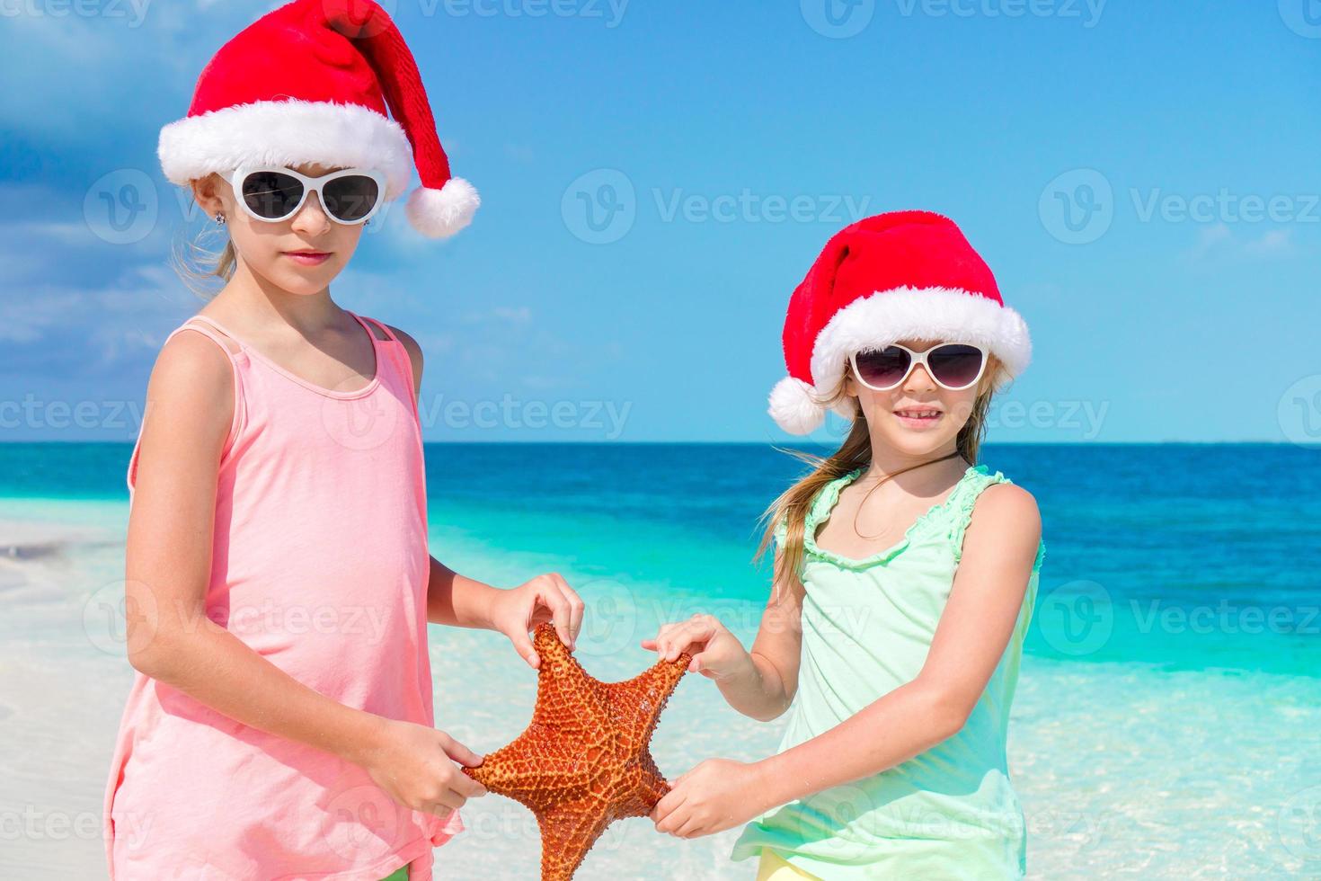 Adorable little girls on Christmas holidays on the beach photo