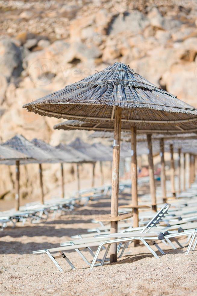 sillas de playa y sombrillas de madera para vacaciones en la playa en grecia foto