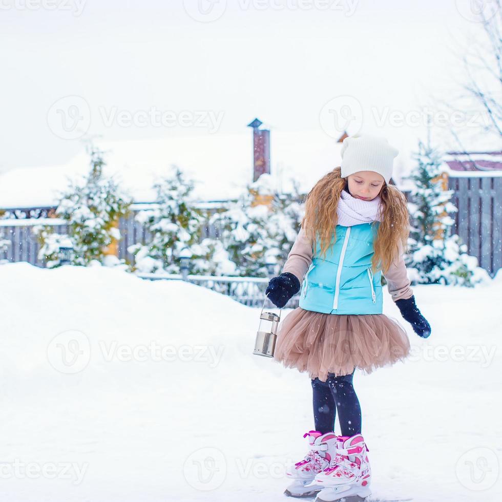 adorable niña de moda patinando en la pista de hielo al aire libre foto