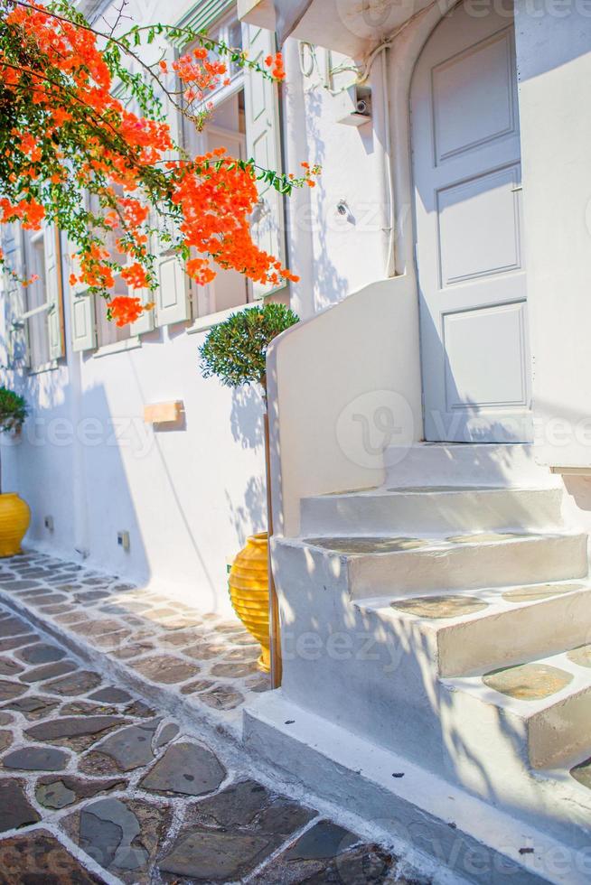 The narrow streets with blue balconies, stairs, white houses and flowers in beautiful village in Greece. Beautiful architecture building exterior with cycladic style in Mykonos photo