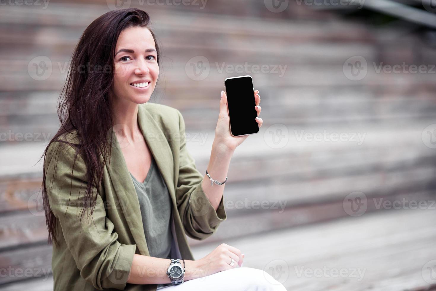 Happy woman with smartphone outdoors in the city photo