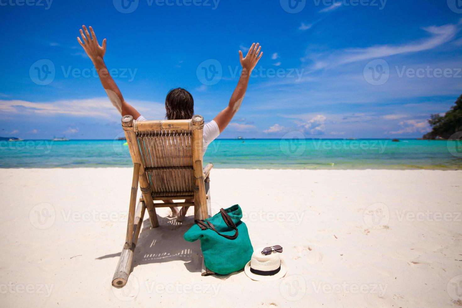 Man relaxing in the wooden chair on sand beach photo