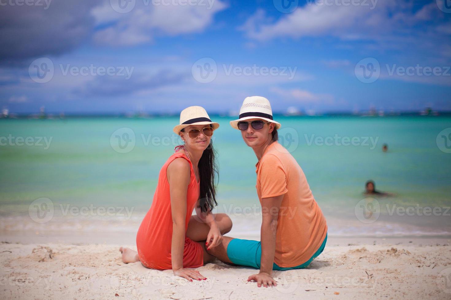 Young couple enjoying each other on a tropical beach and looking at camera photo