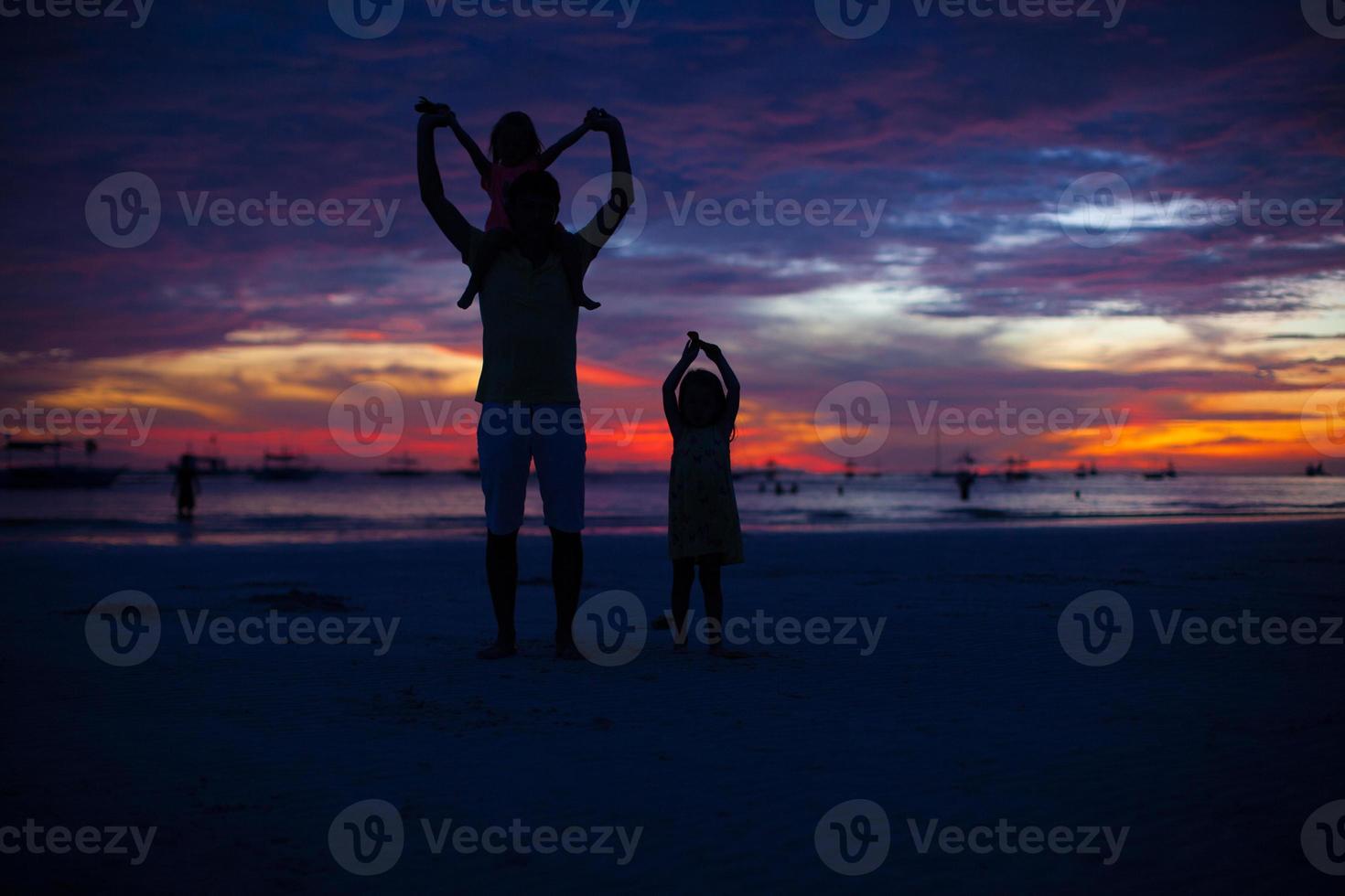 Dad and daughters silhouette in the sunset on the beach on Boracay photo