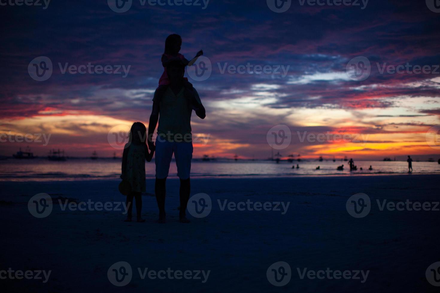 silueta de papá e hijas al atardecer en la playa de boracay foto