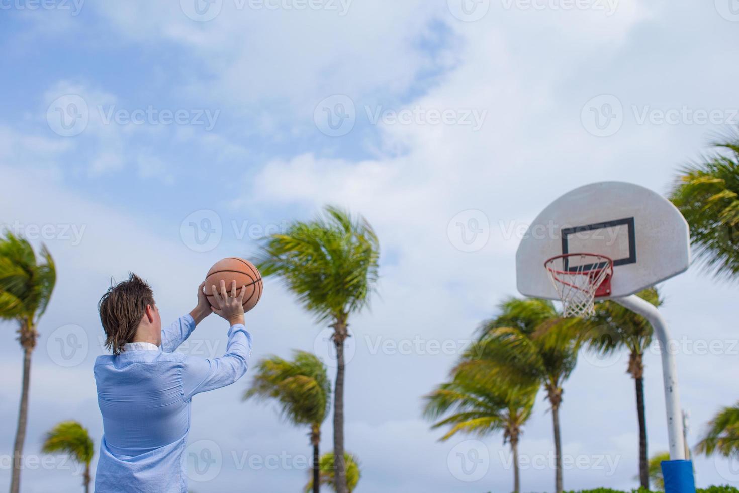 Young man playing basketball outside at exotic resort photo
