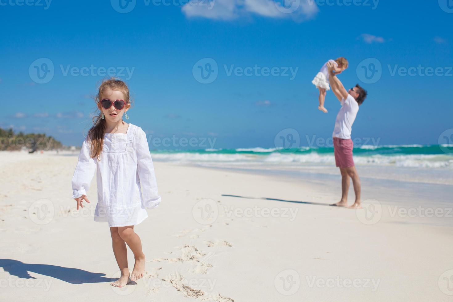 Young dad and his cute daughters having fun on white beach photo