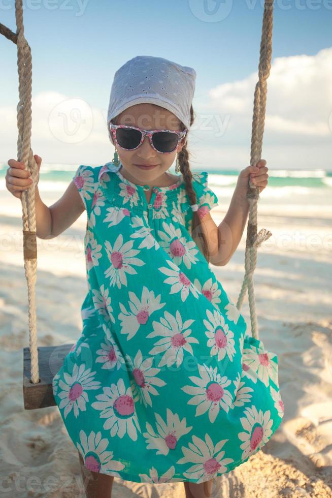 Beautiful little girl swinging on a swing outdoors photo