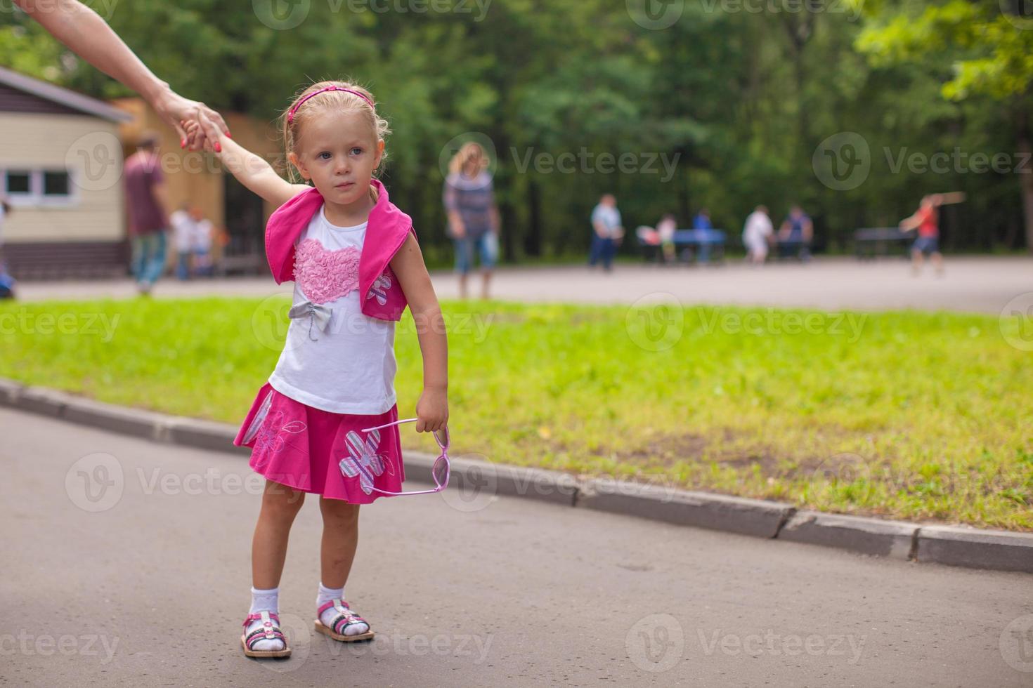 Adorable little girl walking outdoor and having fun in park photo