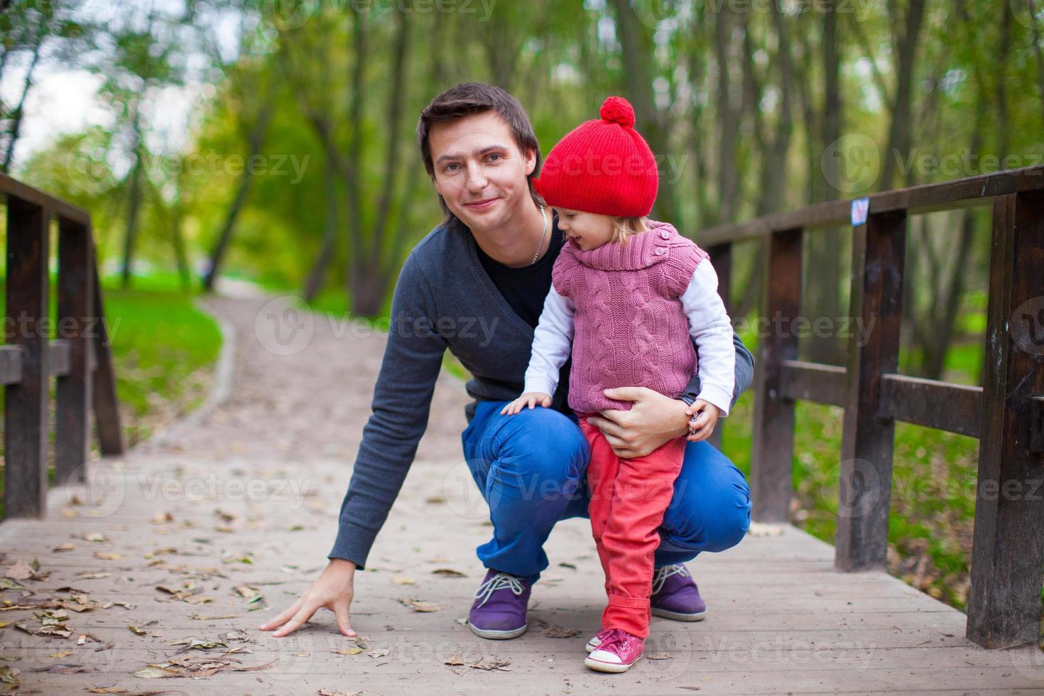 Portrait of Young father walking with his cute daughter in autumn park photo