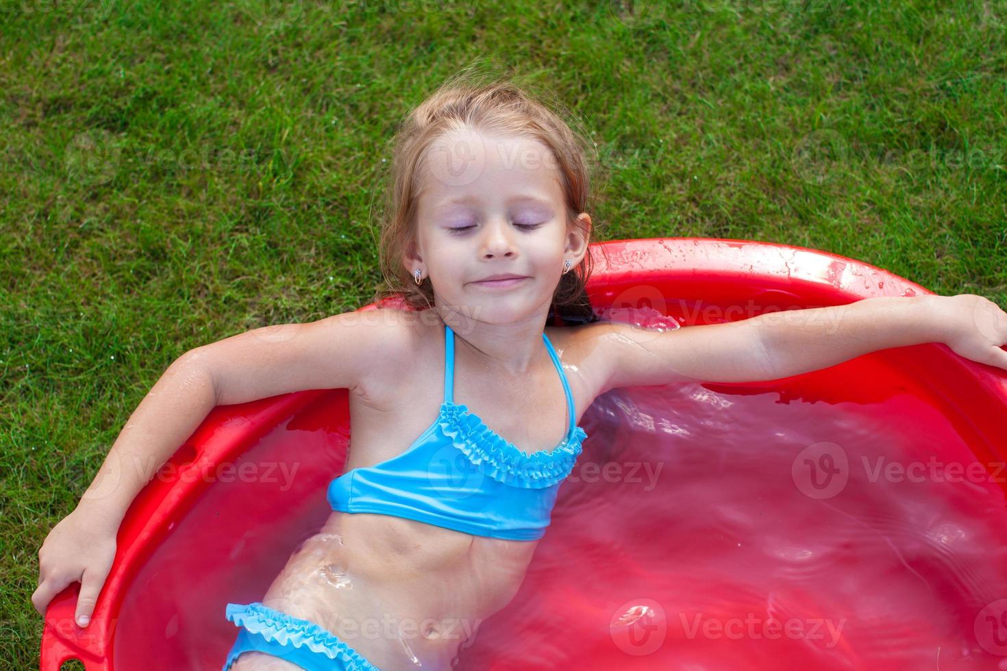 charming little girl enjoying her vacation in the pool outdoors photo