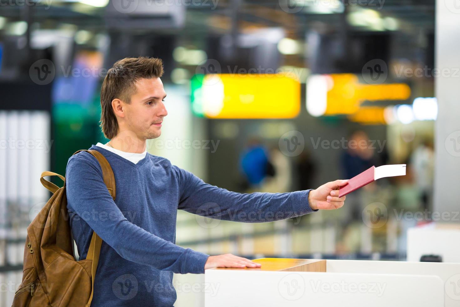 Beautiful man with passports and boarding passes at the front desk at airport photo
