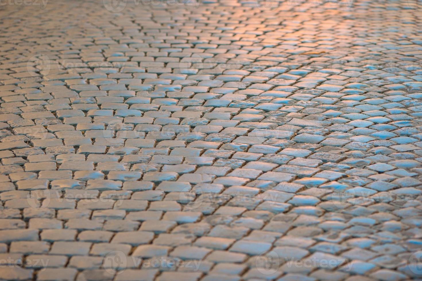 Ancient Roman street lit by a late afternoon sun. Part of a traditional cobbled street in Rome, Italy, showing hundreds of basalt cobble stones in situ, stretching away into the distance. photo