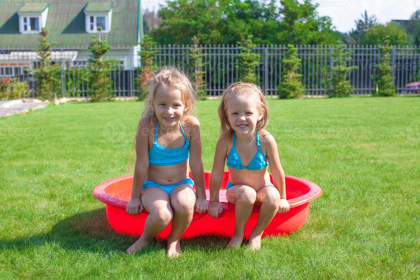 Two little sisters frolicing and splashing in their yard photo